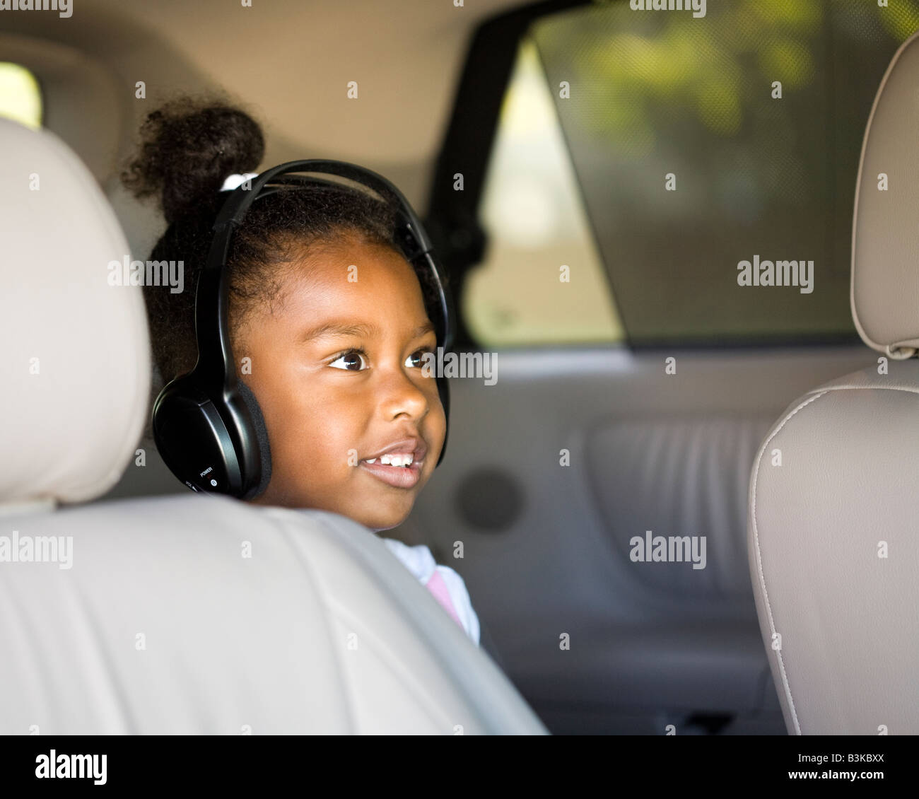 Little girl watches a DVD in the minivan with headphones Stock Photo