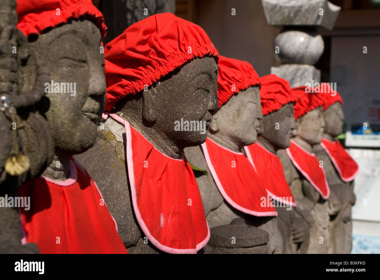 Stone Jizo statues are decorated with red bibs and hats Stock Photo Alamy