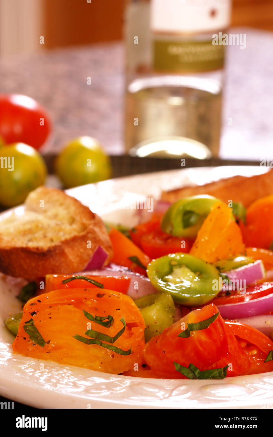 Plate with an heirloom tomato and basil salad Stock Photo - Alamy