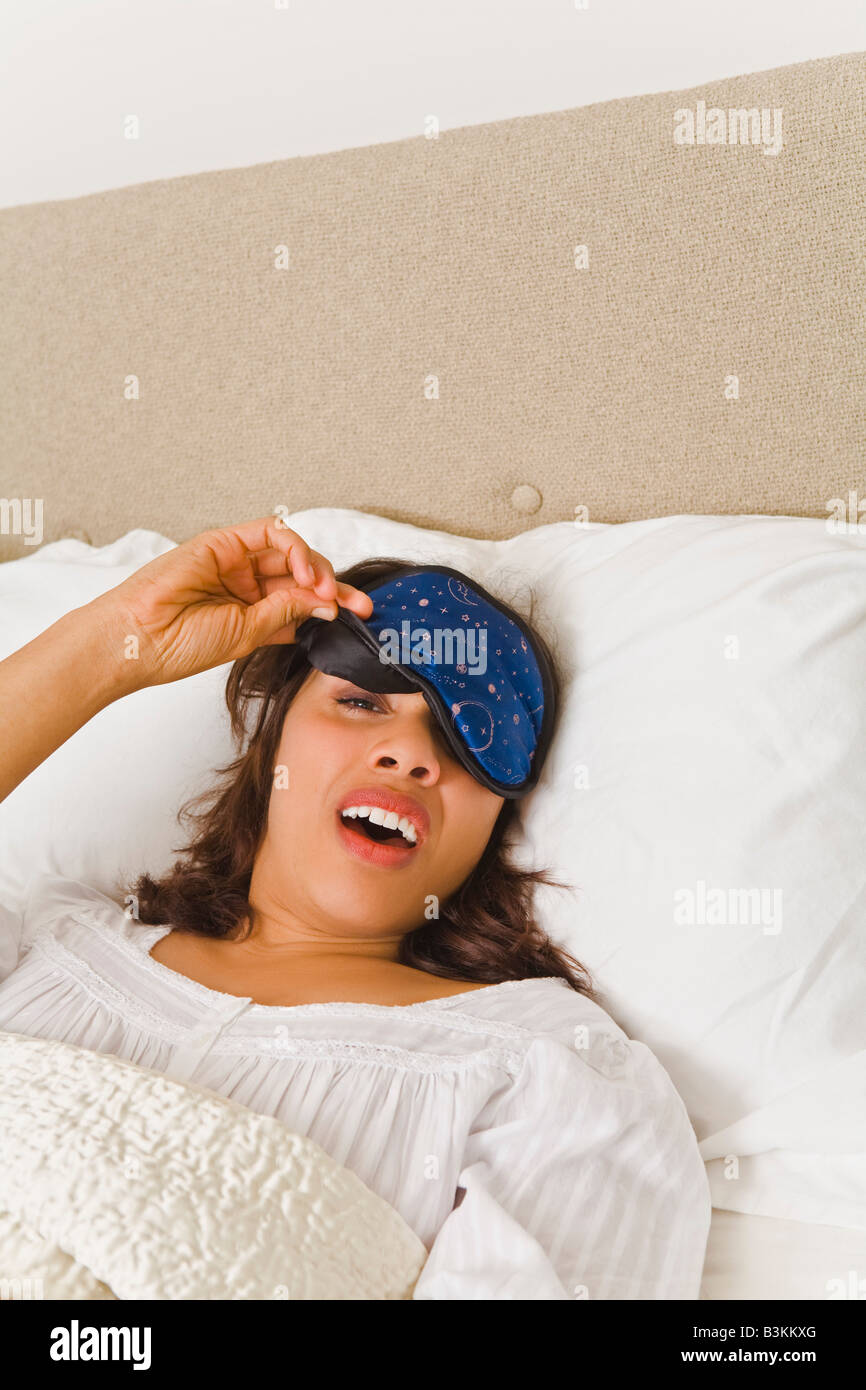 Woman lifting eye mask in bed Stock Photo Alamy