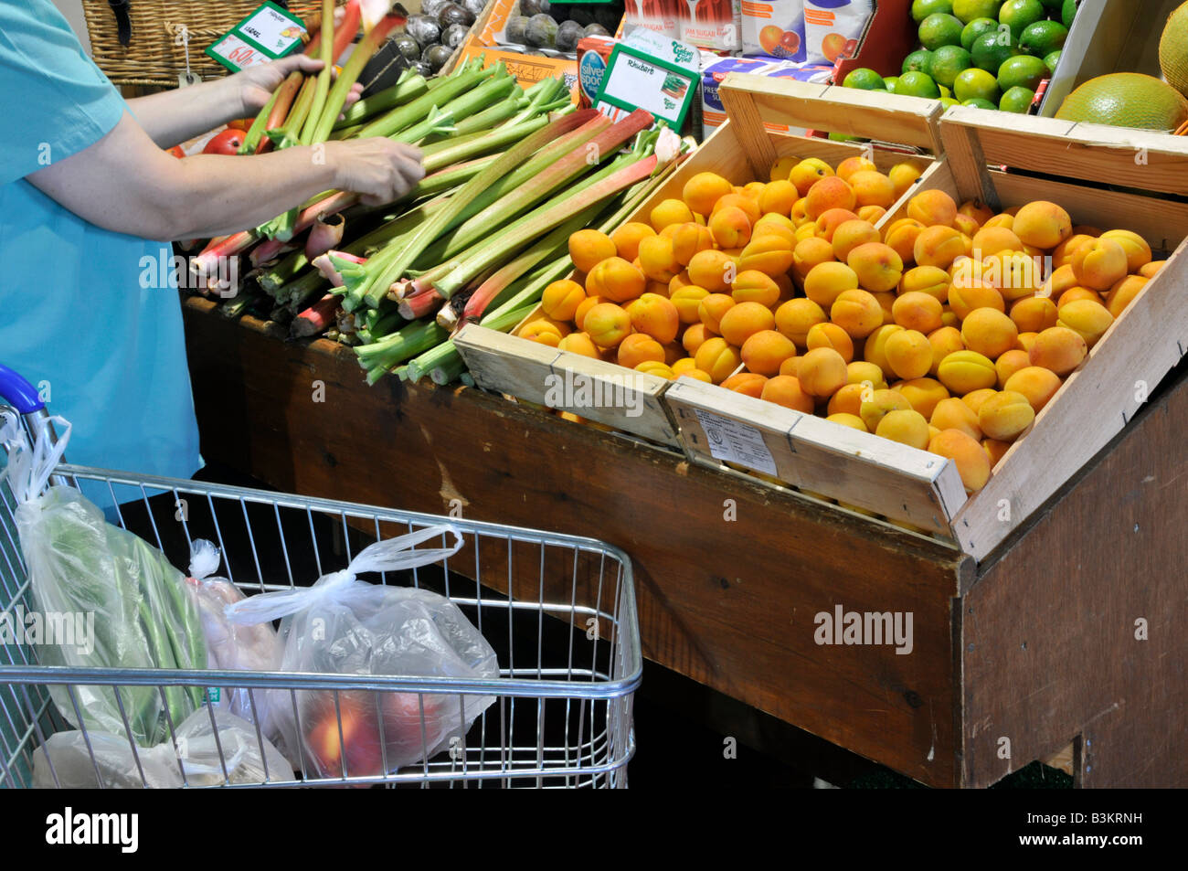 Interior of Calcott Hall retail farm shop produce on display woman shopper and trolley self service selection of rhubarb Brentwood Essex England UK Stock Photo