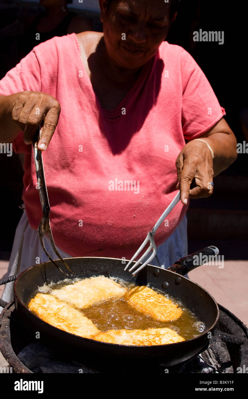 A woman cooking  fried cheese at a street stall. She is frying  with a pan on the side walk in Granada Nicaragua Stock Photo