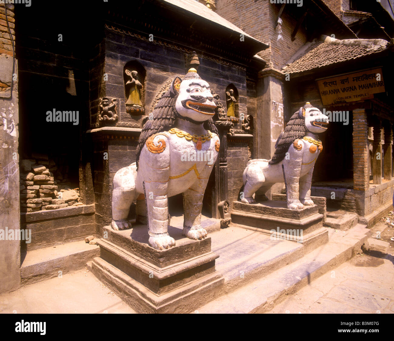 Statues guard the entrance to the Golden Temple in Patan's Durbar Square Stock Photo