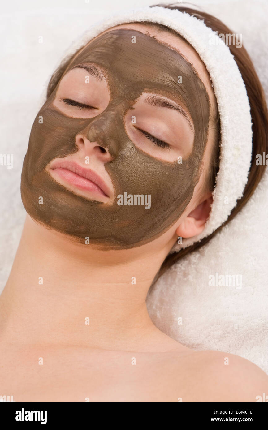 A beautiful young brunette woman rests after having a chocolate face mask applied by a beautician Stock Photo