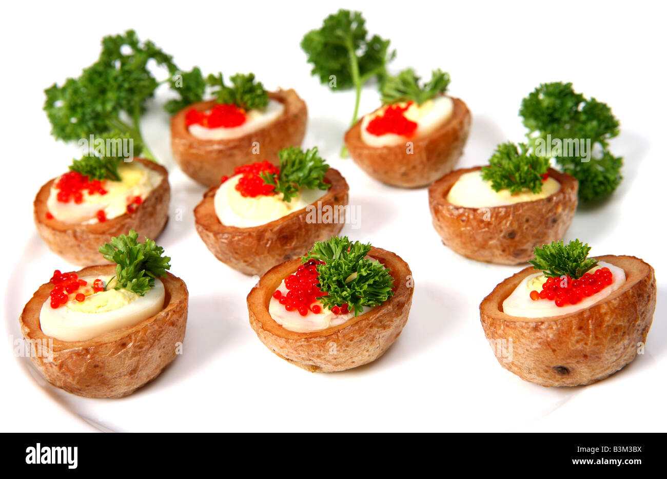 A plate of Quails eggs in tiny baked potato jackets garnished with red lumpfish caviar and parsley Stock Photo