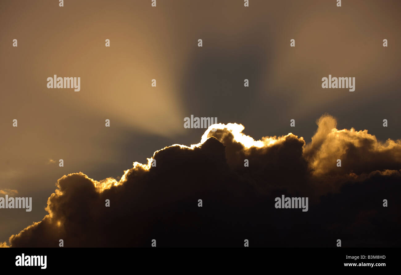 The bright rays of a setting sun burst out from a storm cloud Stock Photo