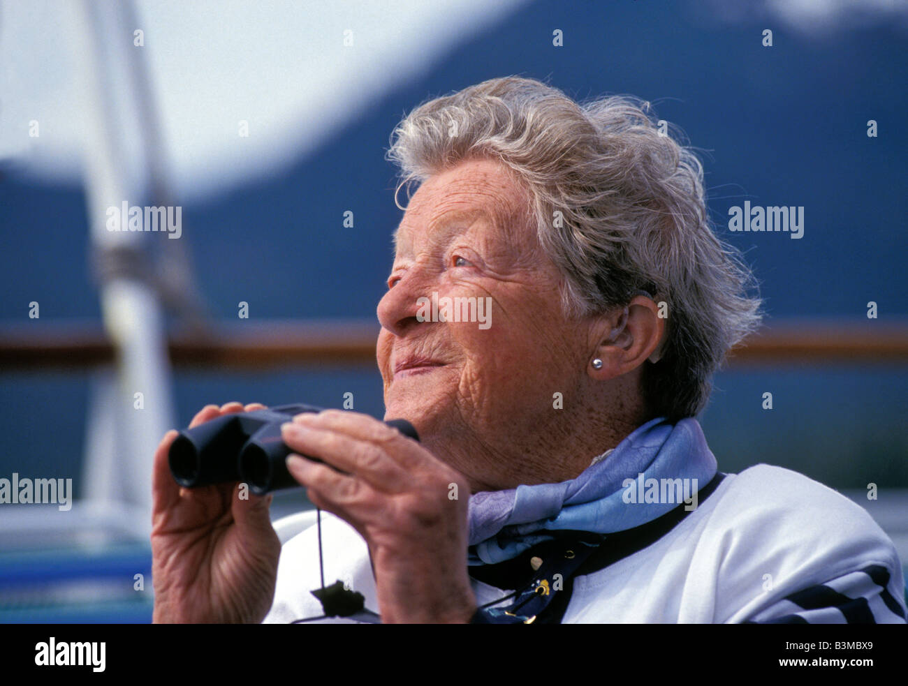 Portrait of Woman Senior Citizen with binoculars enjoying a day of cruising on a cruise ship in the great outdoors Stock Photo