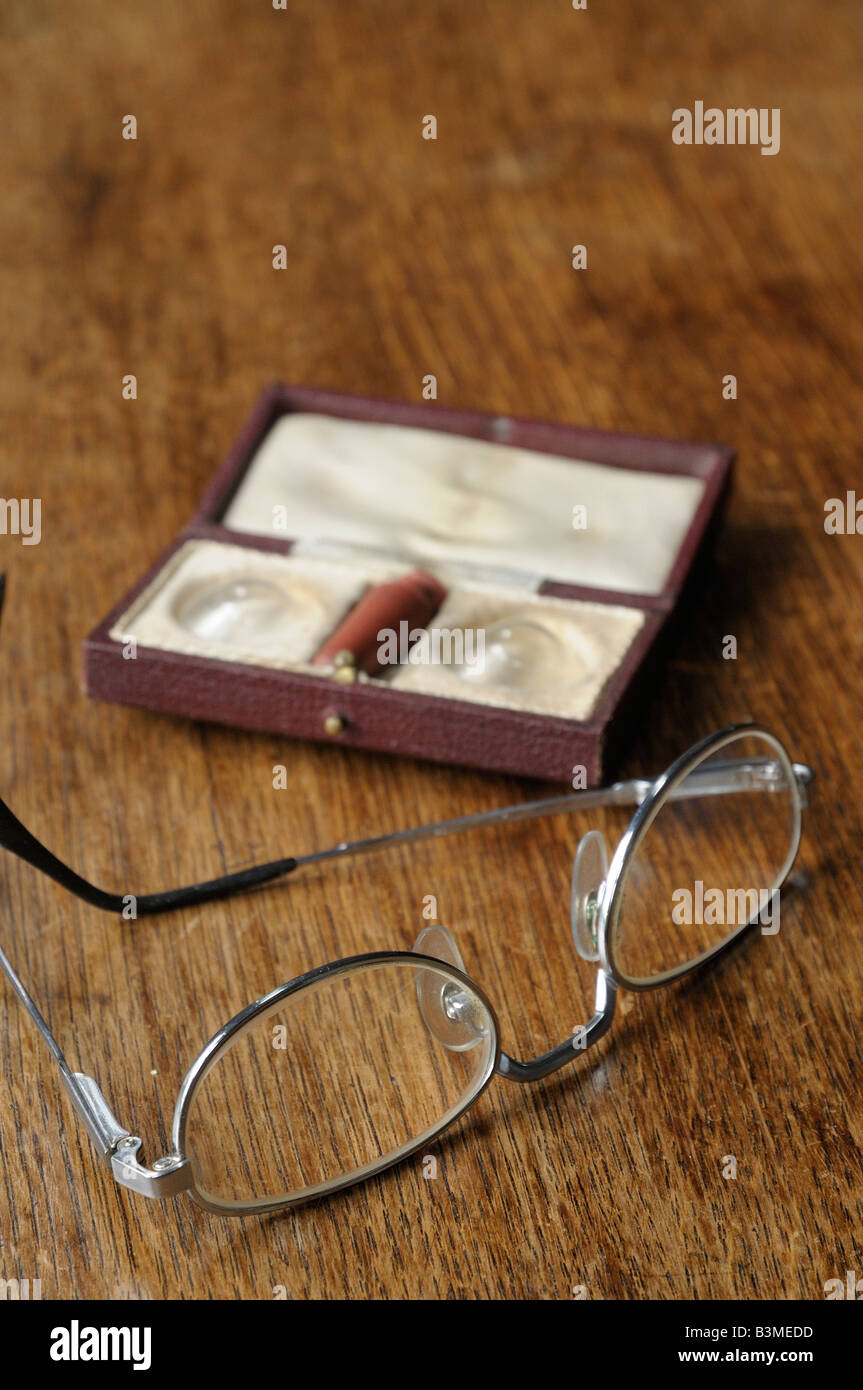 Some old spectacles and old contact lenses, in the original box on a wooden table. Stock Photo