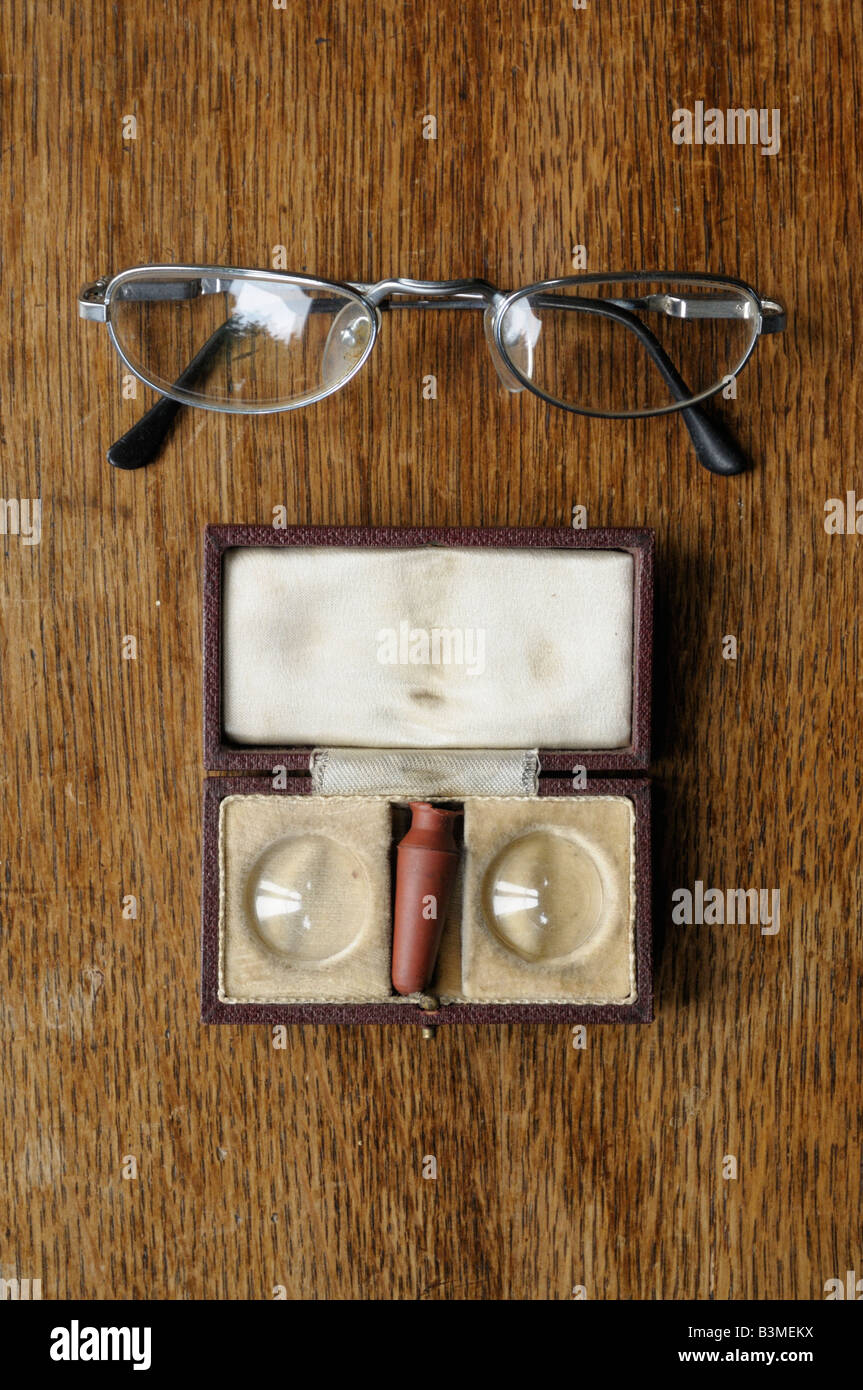 Some old spectacles and old contact lenses, in the original box on a wooden table. Stock Photo