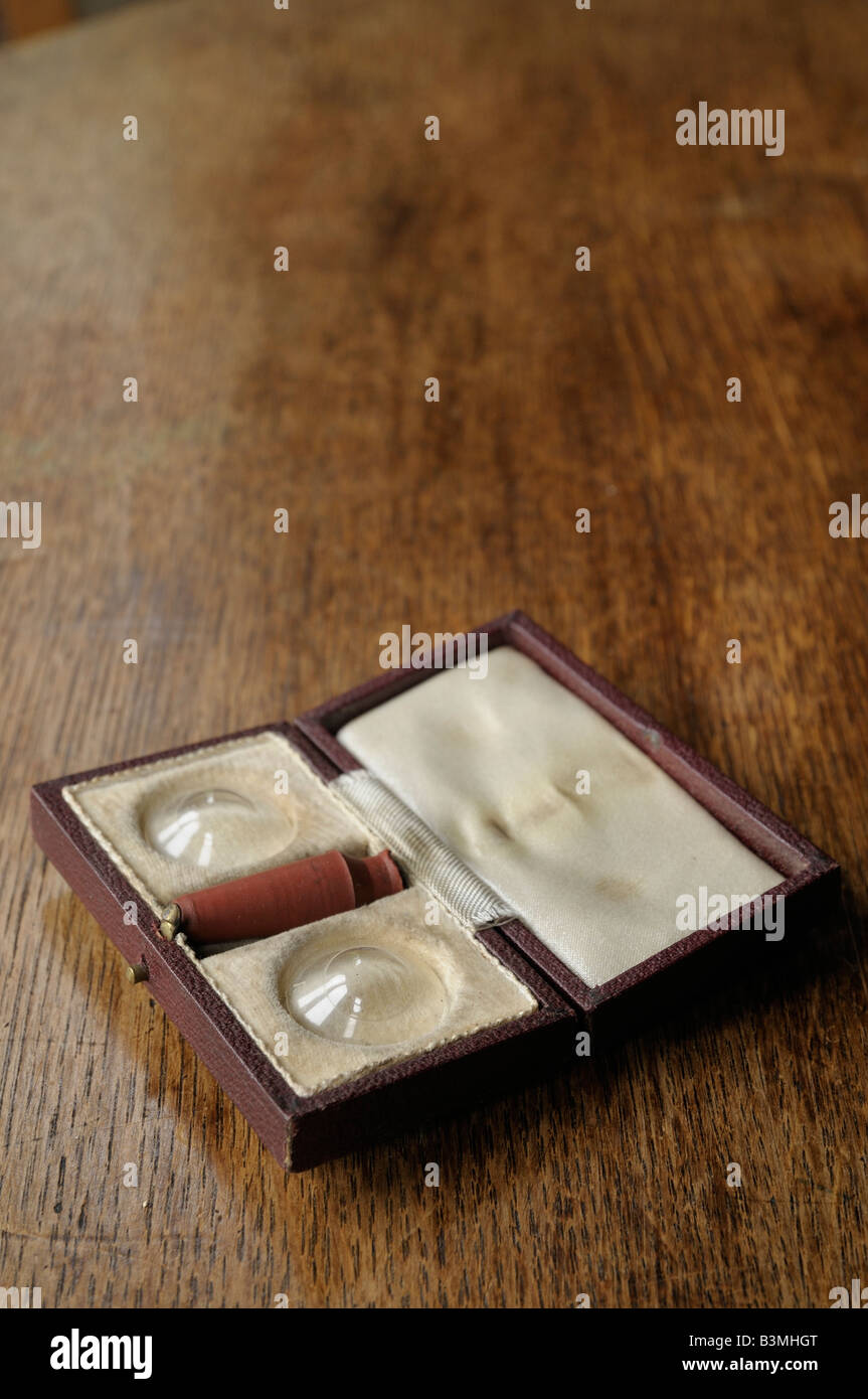 Some old contact lenses, in the original box on a wooden table. Stock Photo