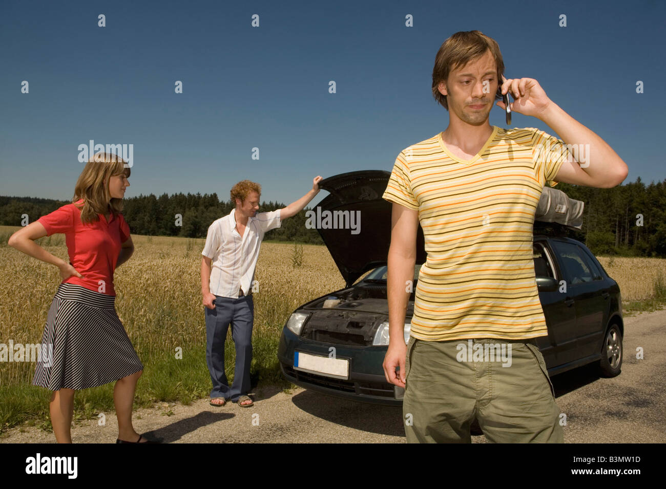 Germany, Bavaria, Three friends with broken down car Stock Photo
