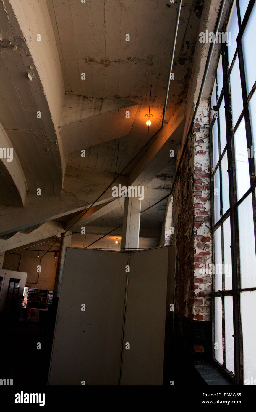 Underside of old concrete bleachers, showing a storage area, single incandescent bulb, and structural elements. Stock Photo