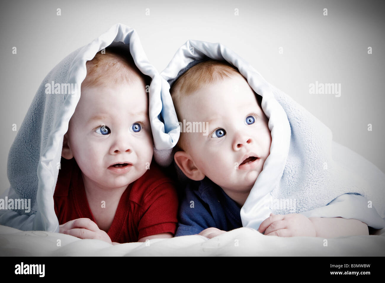 Beautiful redheaded twin babies under blanket Stock Photo Alamy