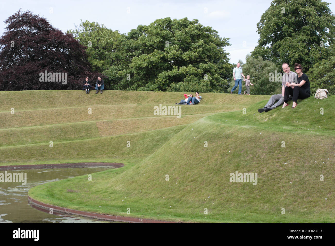 Visitors relax in the sunshine beside the Landform at the Scottish National Gallery of Modern Art, Edinburgh. Stock Photo