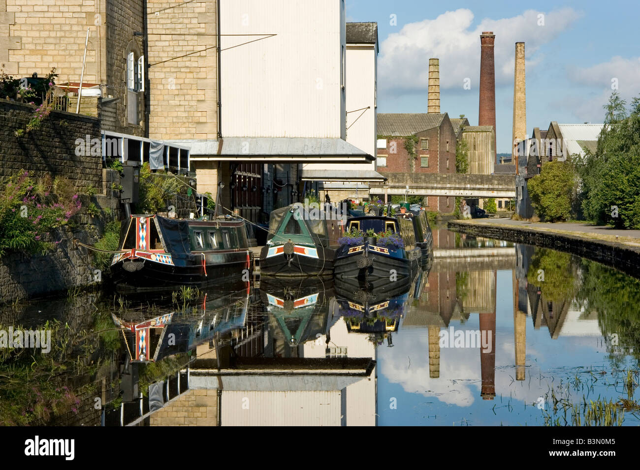 Factory chinmeys are reflected in the Leeds-Liverpool Canal at Shipley, Bradford, West Yorkshire, UK Stock Photo