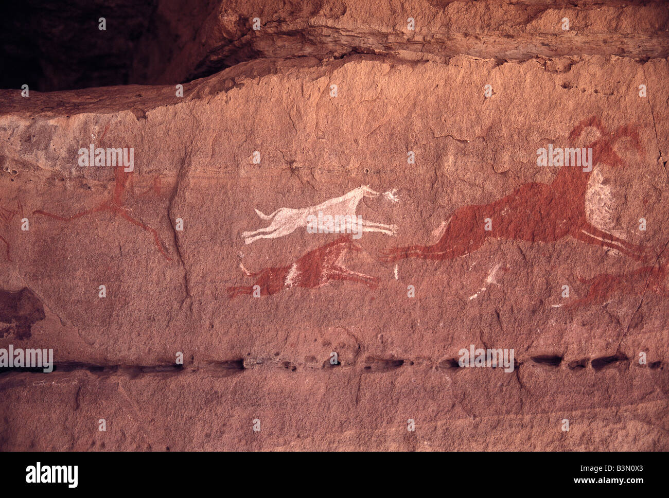 Rock paintings depict a hunter chasing animals at a time when the Sahara Desert was green, Libya. Stock Photo