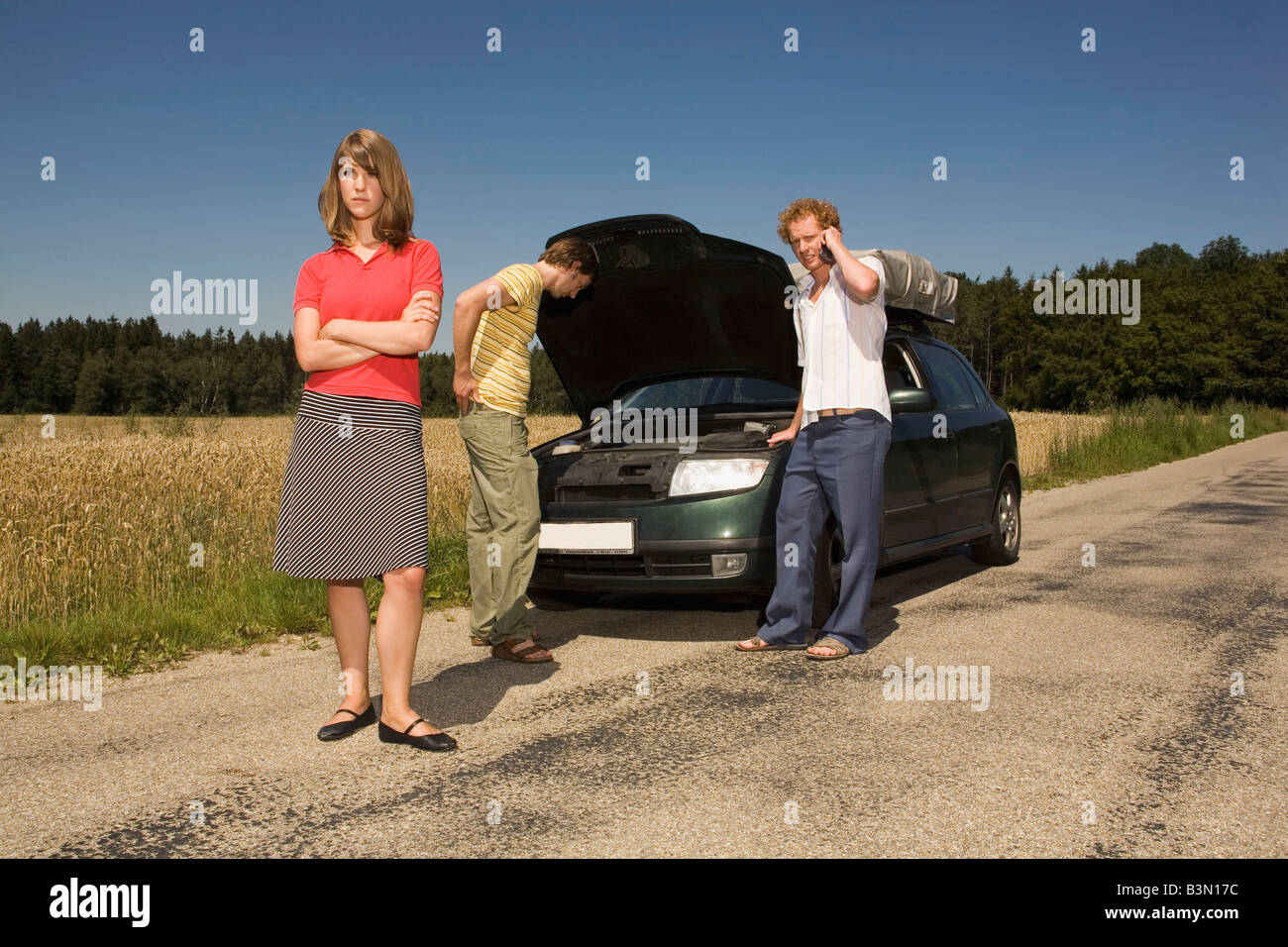 Germany, Bavaria, Three friends with broken down car Stock Photo