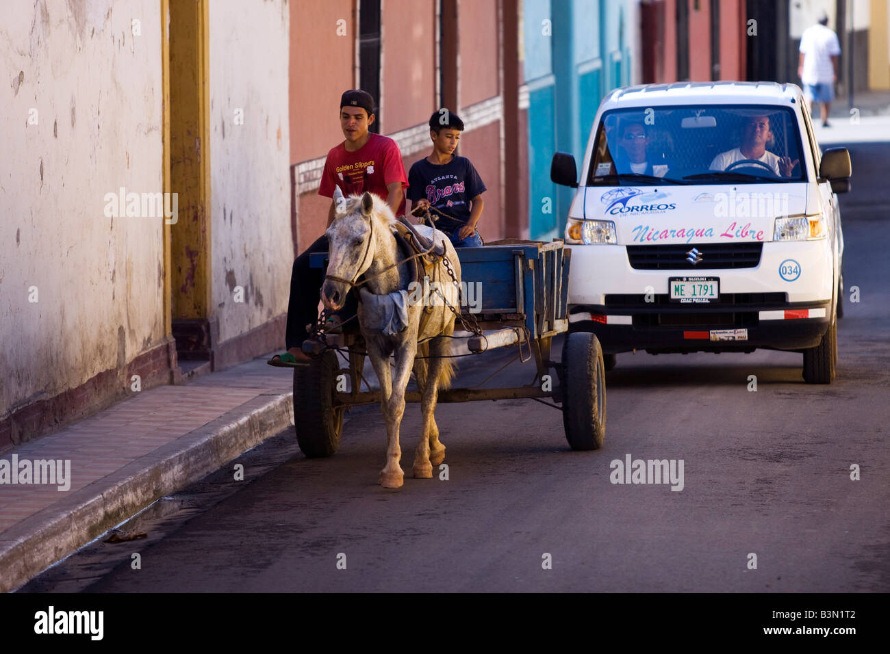 A vehicle with an impatient driver is delayed behind a horse and cart in the narrow streets of Granada Nicaragua Stock Photo