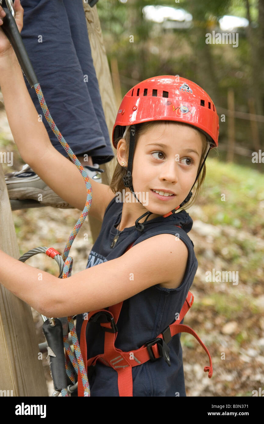 child wearing safety helmet hooks cable to rope in wooded adventure