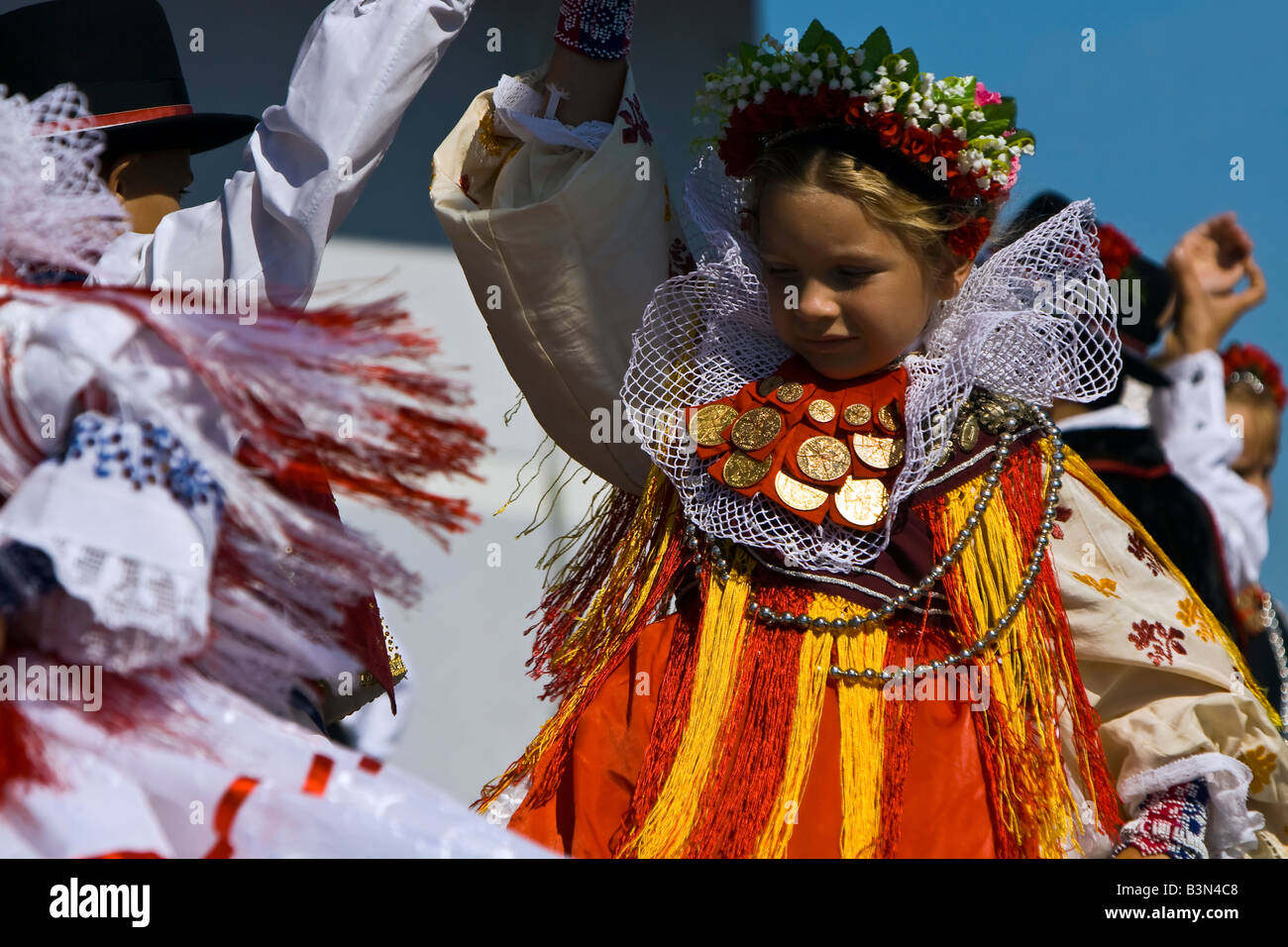 Young girl dancing in the Croatian traditional dress with ducats on the dress and headdress on a folklore festival in Croatia. Stock Photo