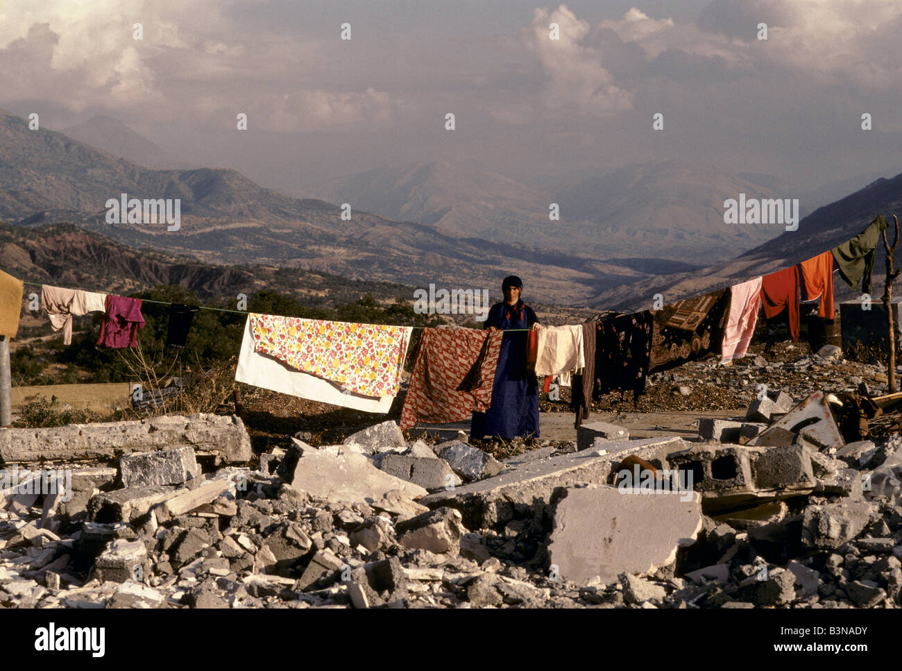 WOMAN HANGS OUT WASHING OVER THE RUBBLE OF HER HOME IN THE BARZAN VALLEY. THE AREA WAS DESTROYED BY IRAQI GOVERNMENT FORCES Stock Photo