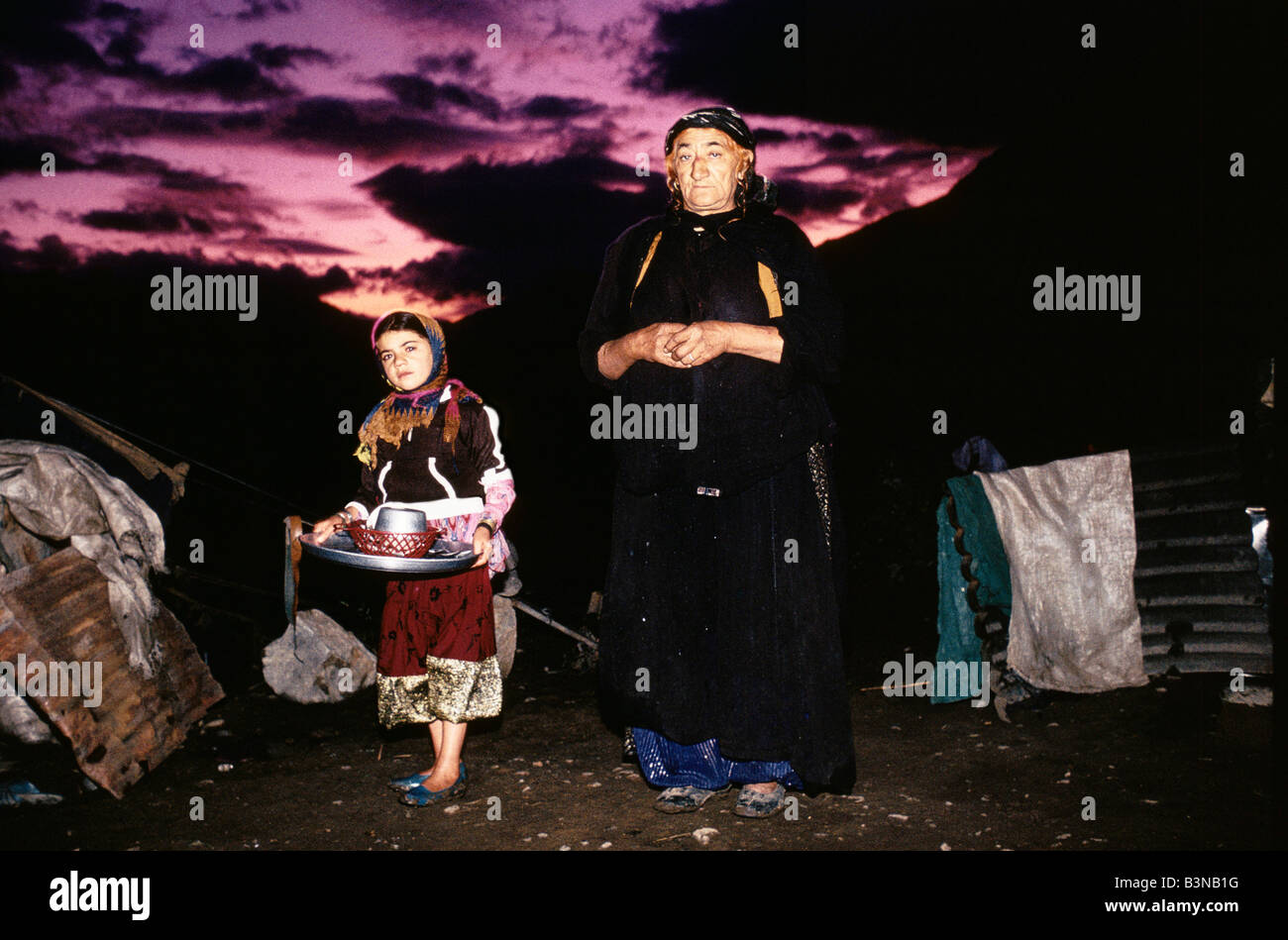 KURDISTAN', WOMAN & CHILD STANDING AGAINST A PURPLE & RED SUNSET IN CHOWMAN, OCTOBER 1991 Stock Photo