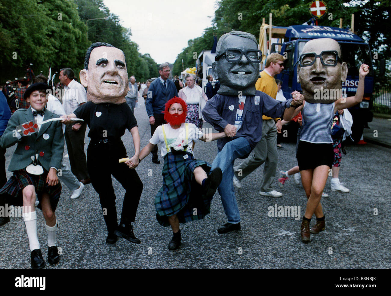 Andrew Wilson and Scott Smith join people wearing paper mache heads resembling heads of state at the Edinburgh Festival parade Stock Photo