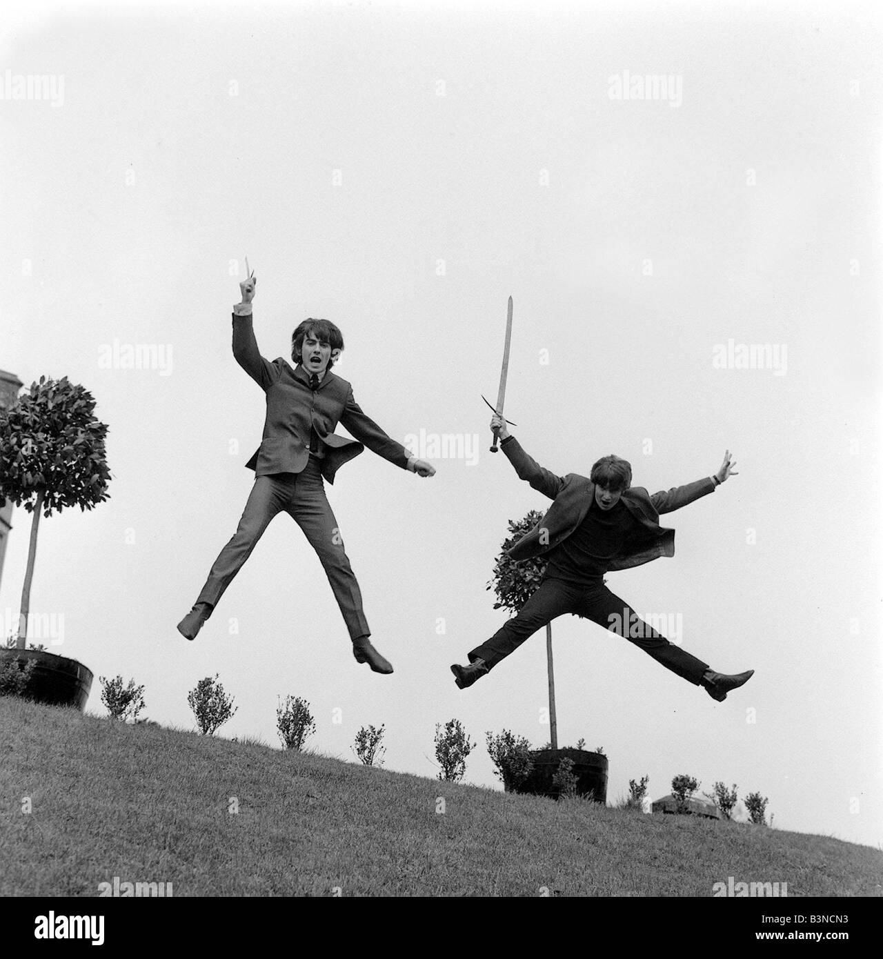John Lennon March 1964 and George Harrison bent the rules of croquet when they tried their hands at the game in the grounds Dromoland Castle Ireland tiring of croquet they changed to some friendly sword play Stock Photo