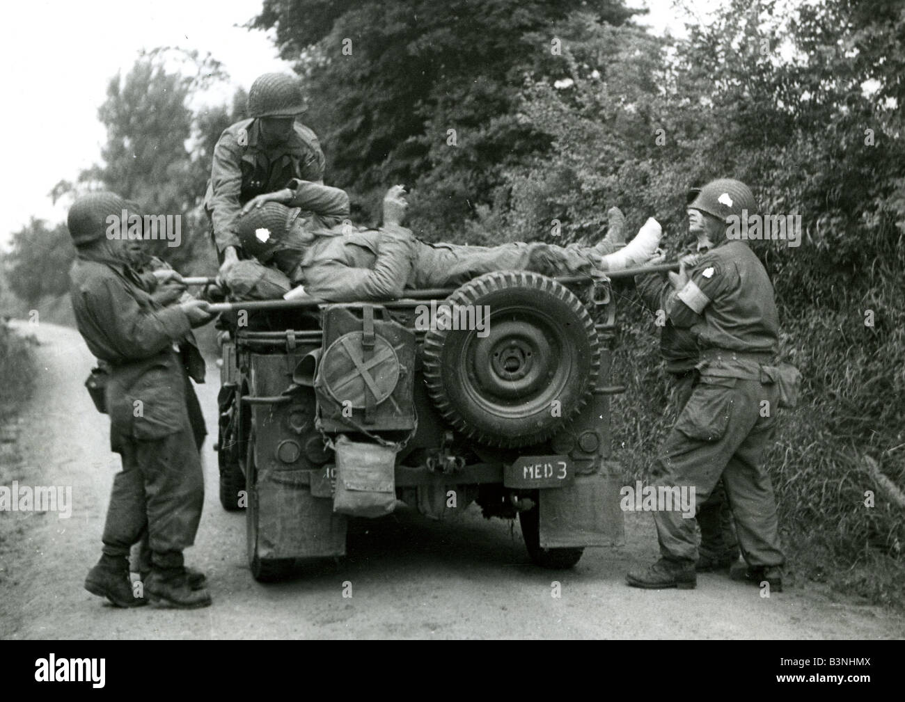 NORMANDY LANDINGS  US casualty is loaded abord a Jeep on 8 June 1944. Unit insignia have been covered by wartime censor. Stock Photo