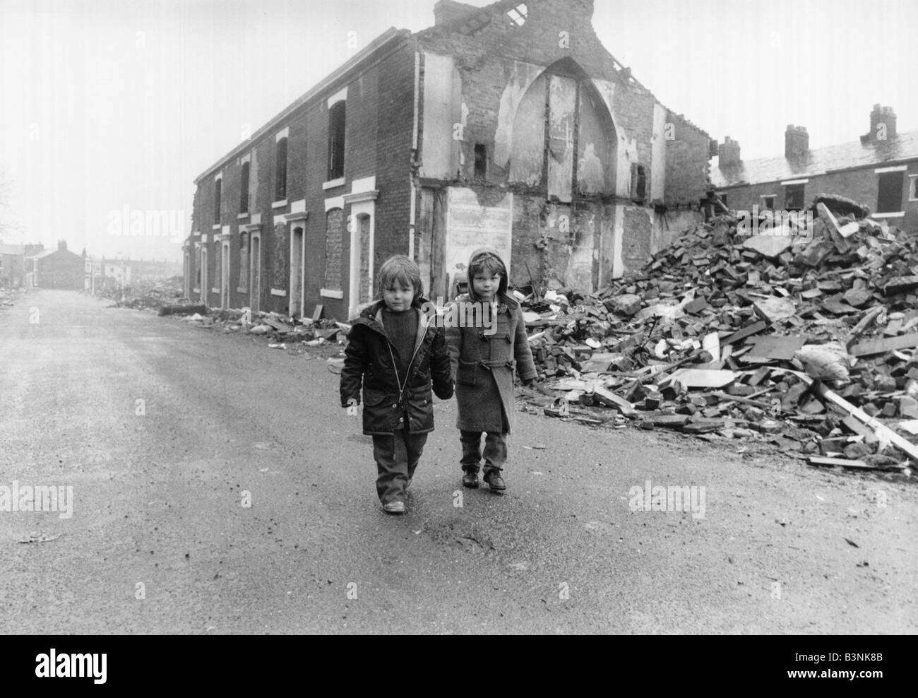 Two boys walk pass the partially demolished row of terrace houses in Blackburn May 1987 Stock Photo
