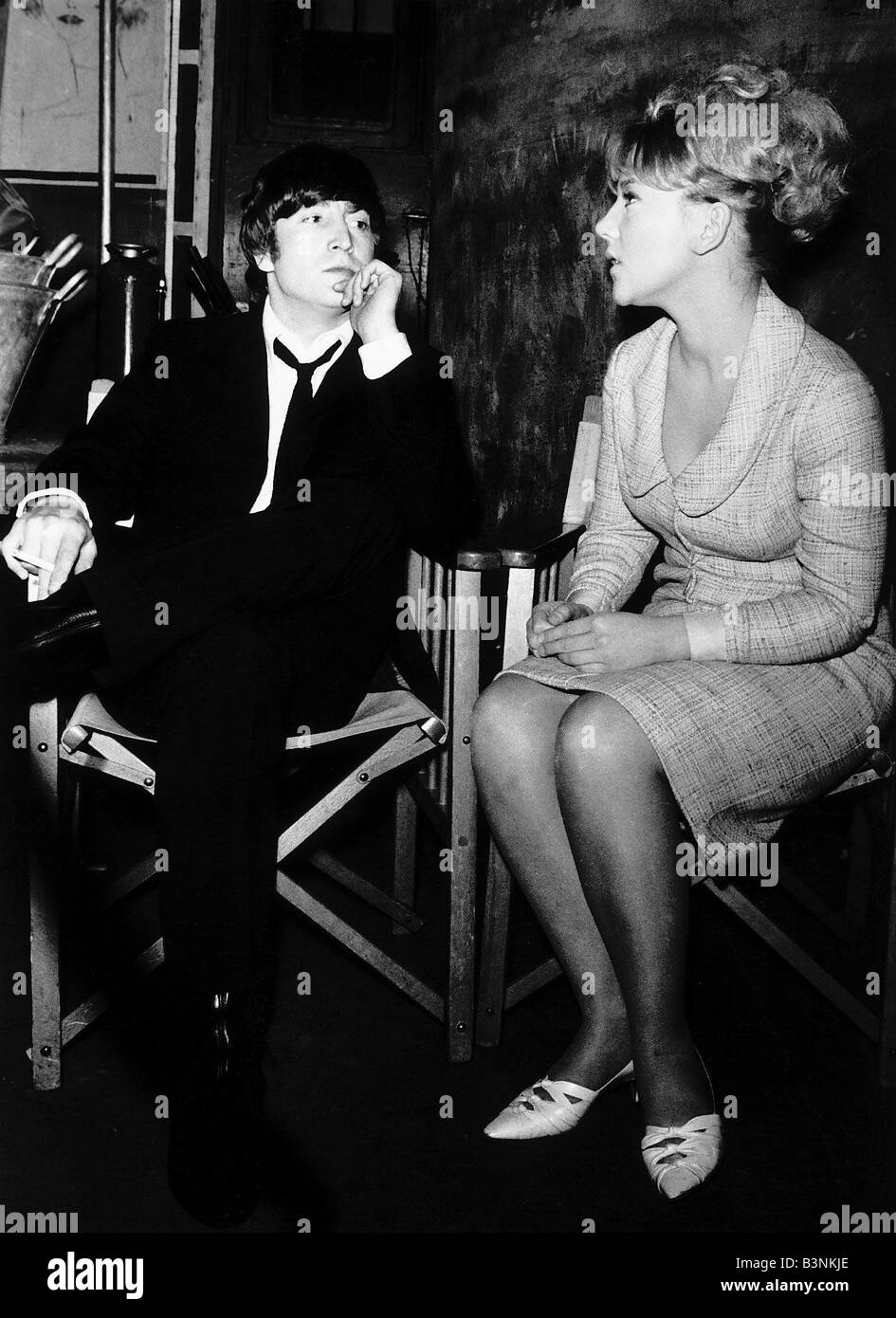 John Lennon Song Writer of the Beatles talking with a woman as he sits in his chair March 1964 Stock Photo