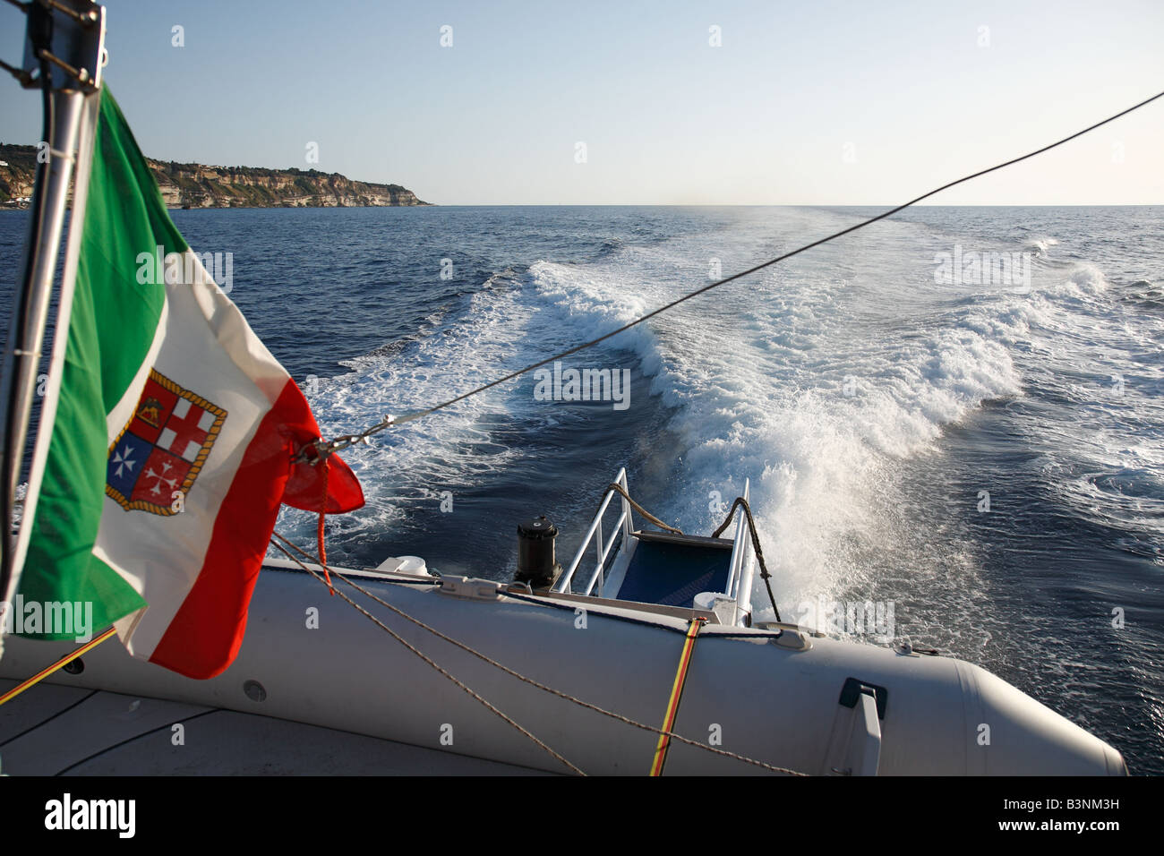 Italy, Sicily, Province of Messina, Aeolian Islands, Lipari Islands, Tyrrhenian Sea, Mediterranian Sea, excursion ship on the sea, stern, italian flagg with arms of the merchant navy, coat of arms, maritime flagg, gangway, water, waves, wake, clearway Stock Photo