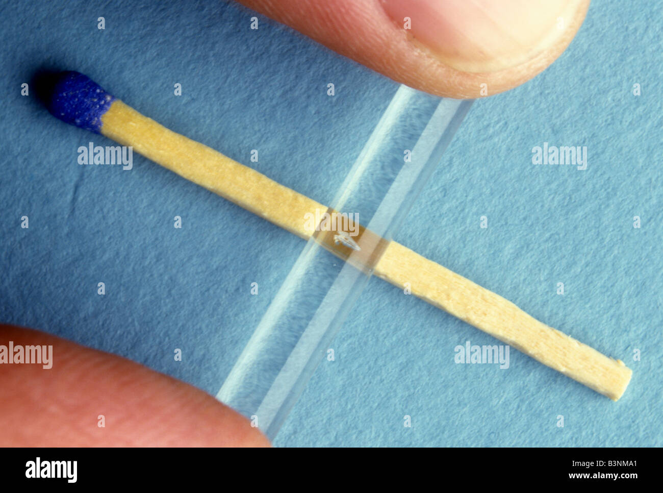 How to cut a glass rod. First file a small nick and then break glass rod over a match stick Stock Photo