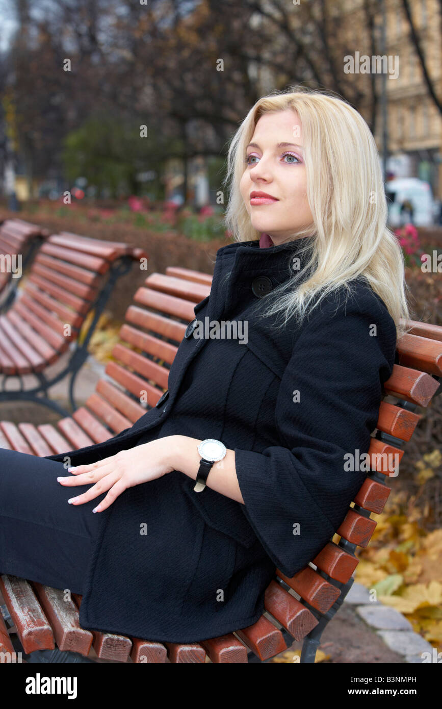 Young woman sitting on bench in park Stock Photo - Alamy