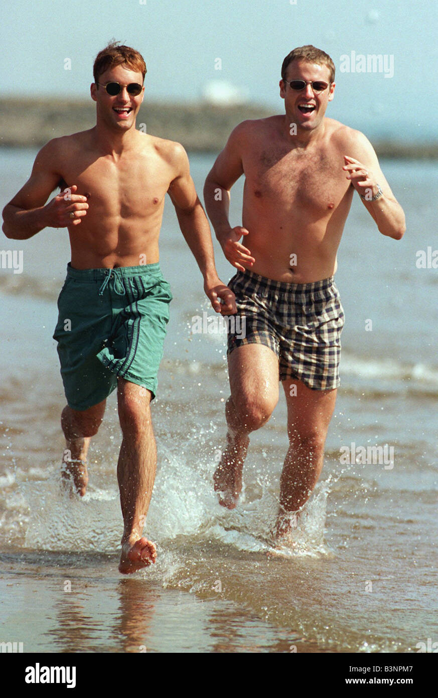 Paul L wears swimming shorts by Moto and Mark wears Speedo checked shorts sunglasses June 1997 Stock Photo