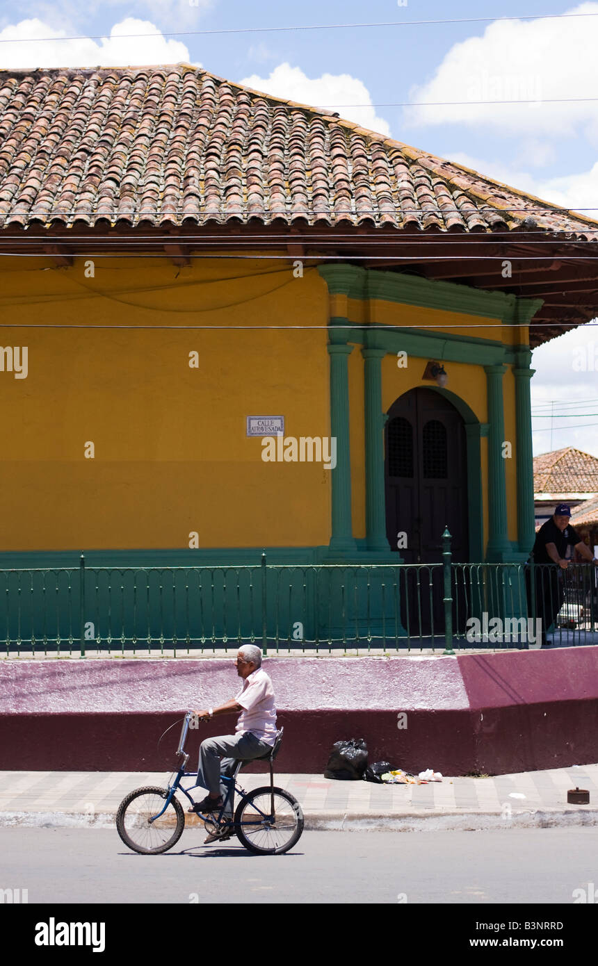 An old man rides by on a Chopper bicycle past a a traditional building in Granada Nicaragua Stock Photo
