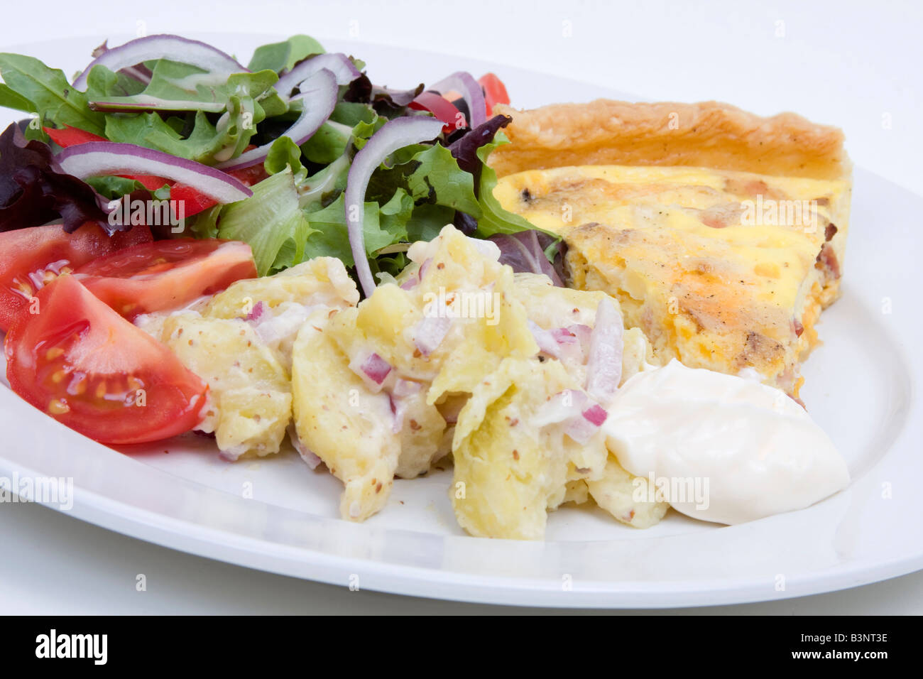 Quiche Lorraine with fresh salad on a white plate Stock Photo