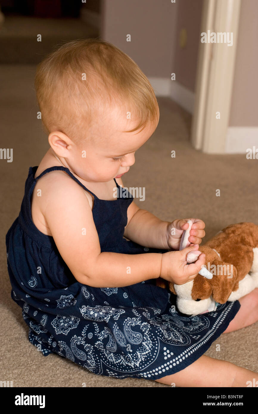 nine month old girl feels the ears of her stuffed animal dog Stock Photo