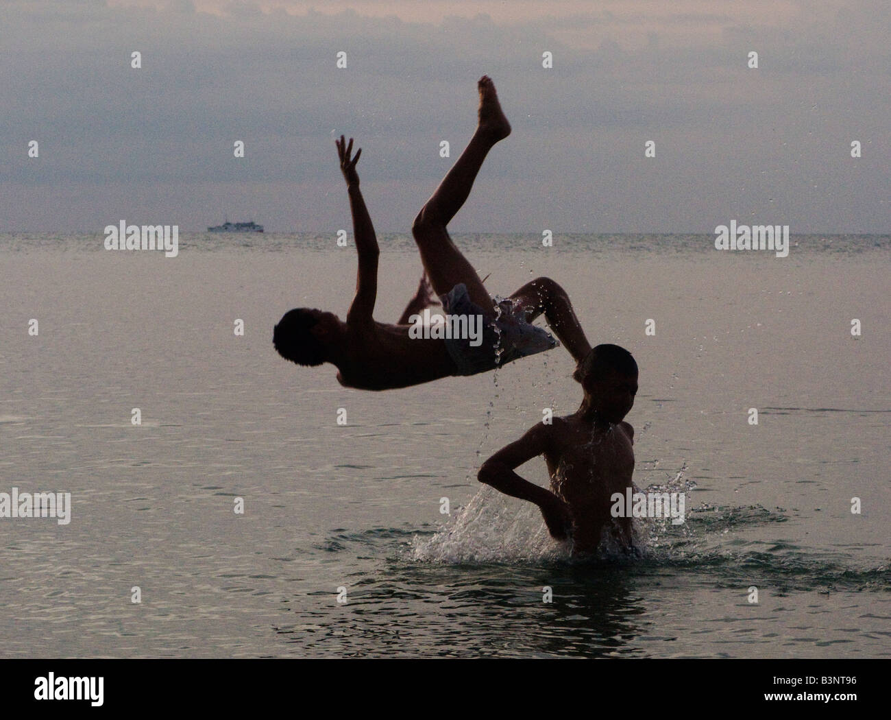 Boy somersaulting off friends shoulders Stock Photo