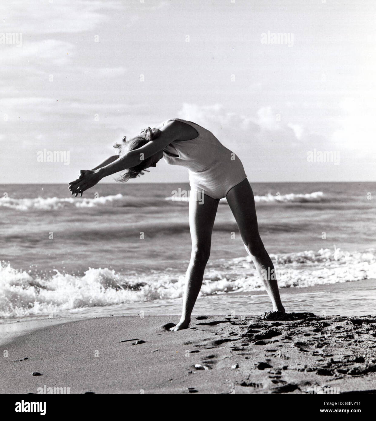 Woman exercising on beach December 1964 1960s Local Caption relaxedimages Stock Photo