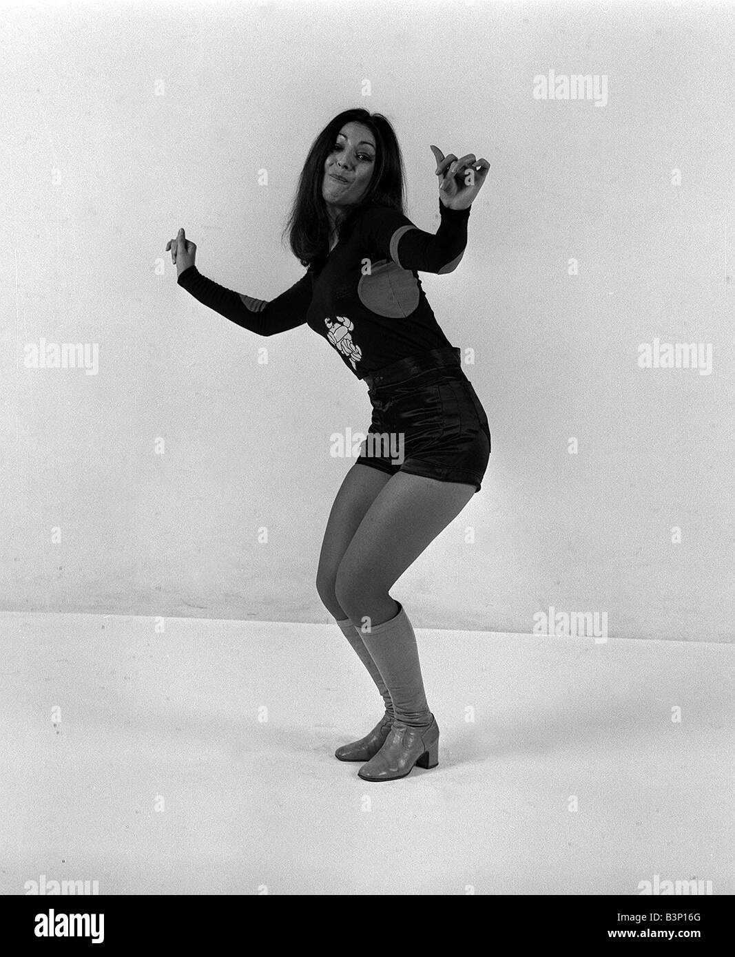 Ruth from Pans People models Mr Freedoms Michelin Man s vest and Black Satin Shorts and knee high boots dancing to her own tune Stock Photo