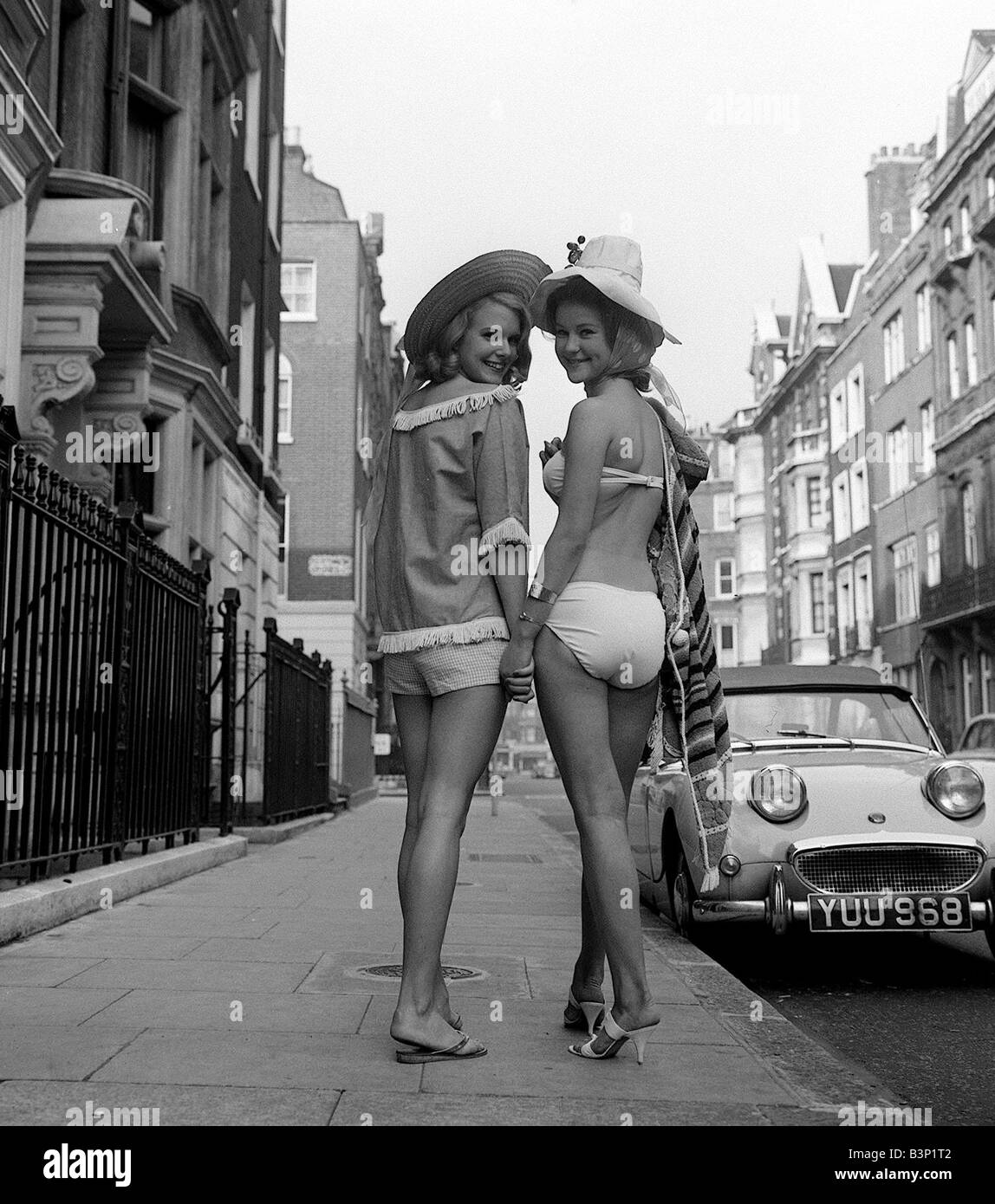Clothing October 1961 LEFT Annabel Maufe 19 rehearses with RIGHT Judy Edwards 16 for the end of term fashion show at The Charm Show for would be models in Welbeck Street London Annabel Pictured wearing canvas navy top with white fringe and pink and white gingham shorts topped with a gigi hat Judy Pictured wearing two piece bikini and floppy hat Stock Photo