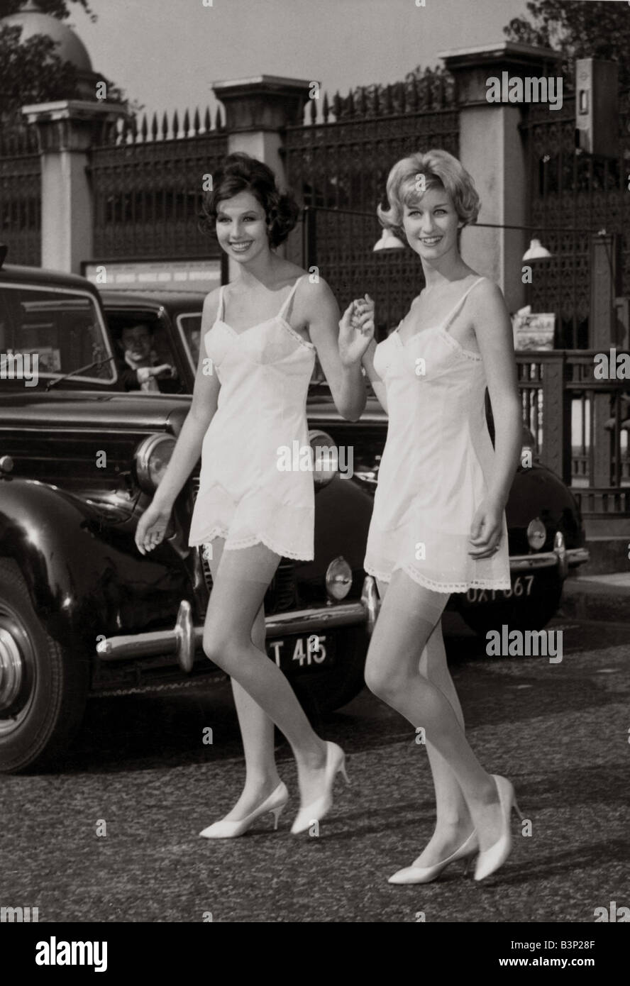 Two models walking by Hyde park corner wearing their slips after slipping  out from a nearby fashion where they were modelling 1960s lingerie October  1959 nightwear fashion women womens woman holding hands