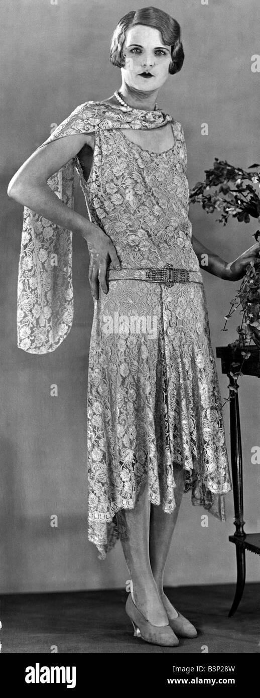 A model wearing a long patterned dress showing the popular uneven hemline 1929 fashion women stylish elegant dresses flapper style shawl scarf 1920s woman 1 1 29 mirror Stock Photo