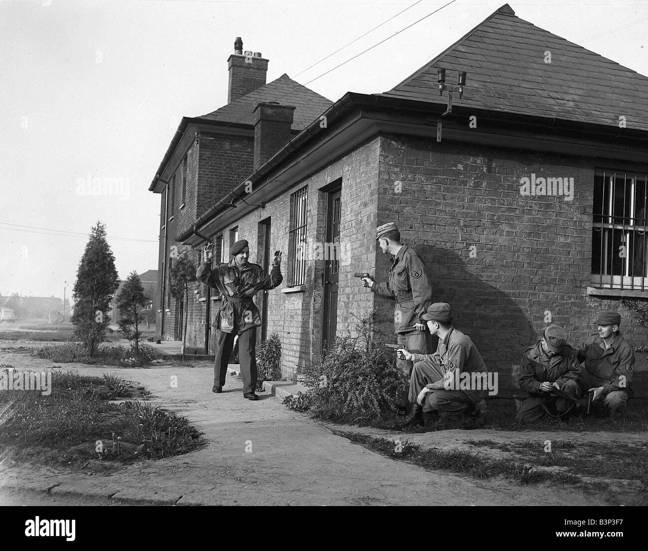 The 18th Parachute Battalion stage a mock attack on an American Aerodrome at Upper Heyford 1952 Two soldiers detain a third threat enemy soldier outside a house Stock Photo