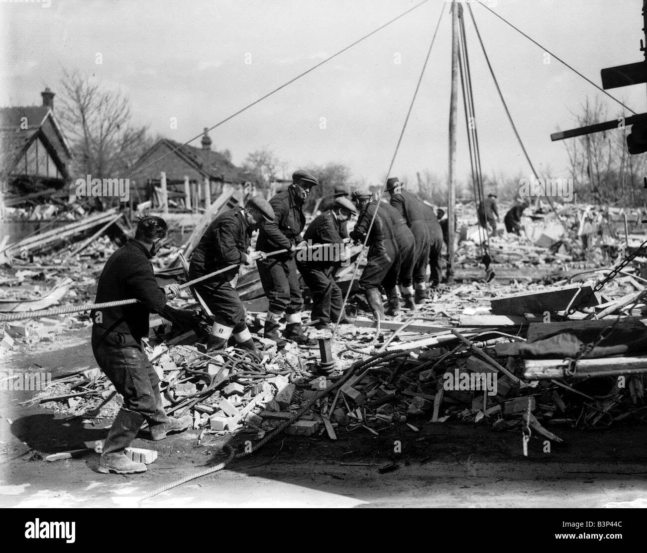 WW2 Air Raid Damage Bomb damage at Chigwell A group of men working together to clear the rubble left by the air raid bombs pulling on a rope Stock Photo