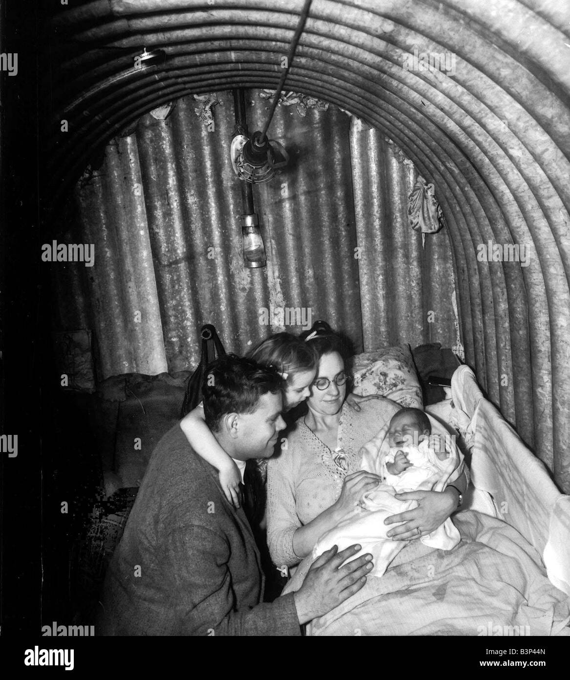 WW2 A family seeks refuge inisde an Anderson Air Raid shelter during the blitz These shelter came in kit form they were made of Stock Photo