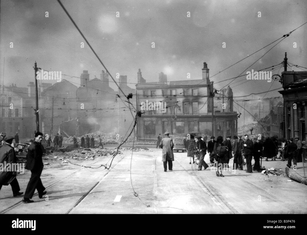 WW2 Air Raid Damage Liverpool Bomb damage in Liverpool civilians walking under damaged tram power lines after the blitz attack of the Germans circa 1940 Stock Photo