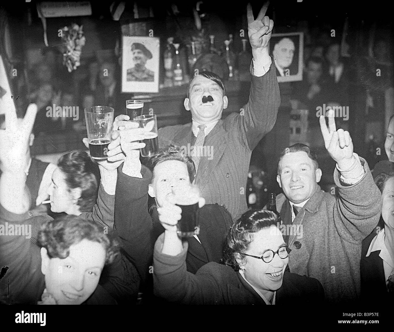VE day celebrations in Lambeth London as man dresses up as Hitler in a pub saluting with beer Stock Photo