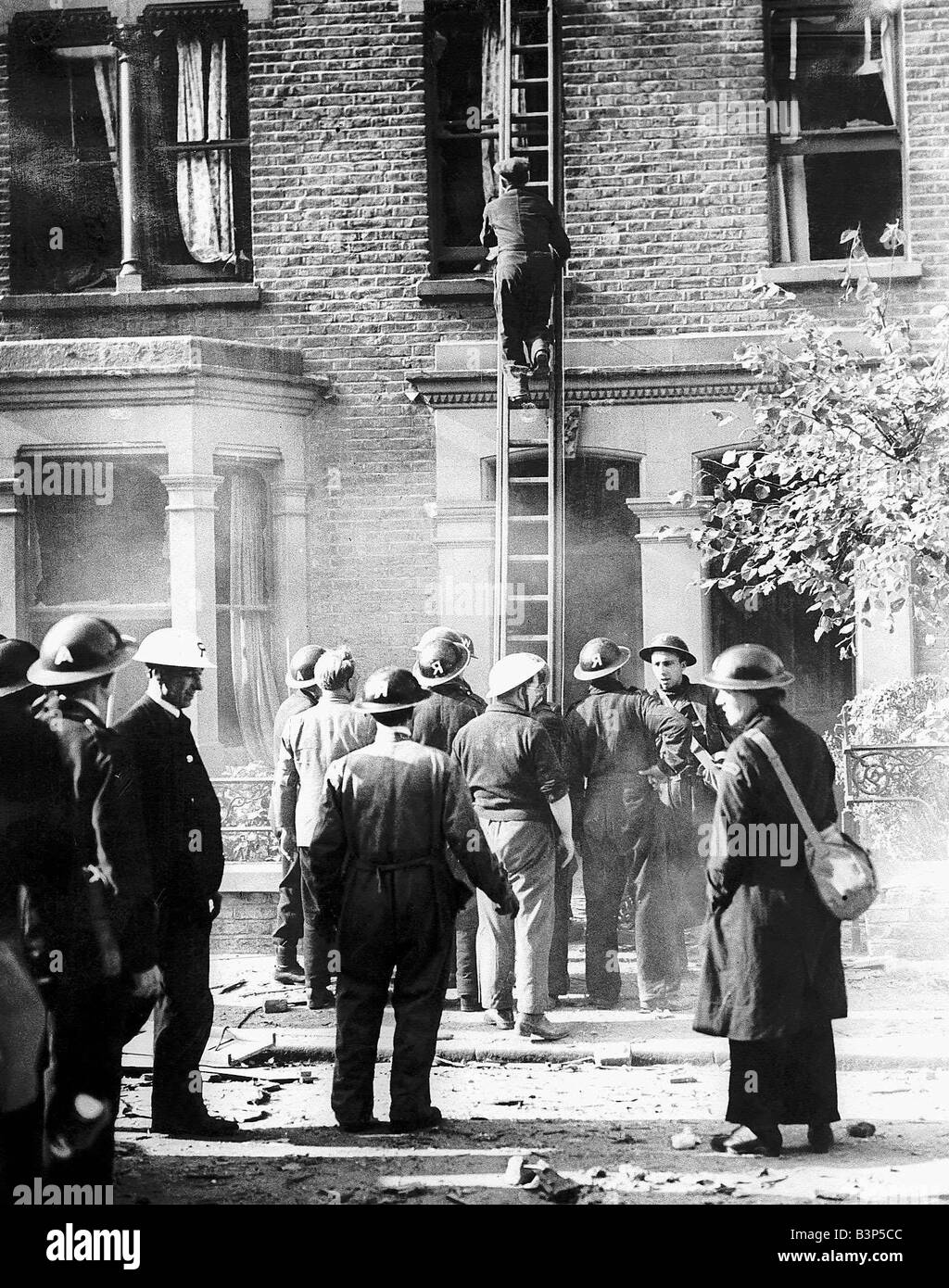 Rescue workers at scene of bomb damaged house during WW2 A man going up a ladder in search of casualties Stock Photo